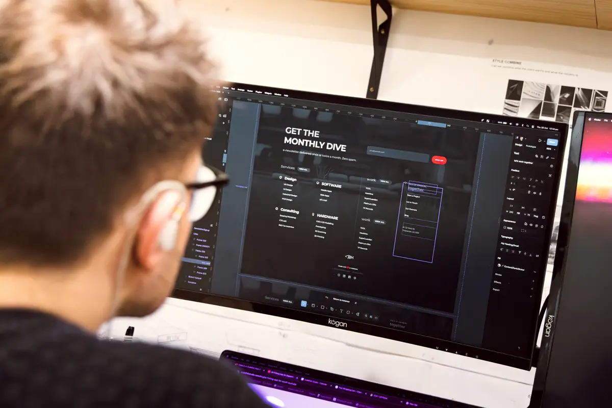 A CodeFish team member editing a website footer design on a monitor
