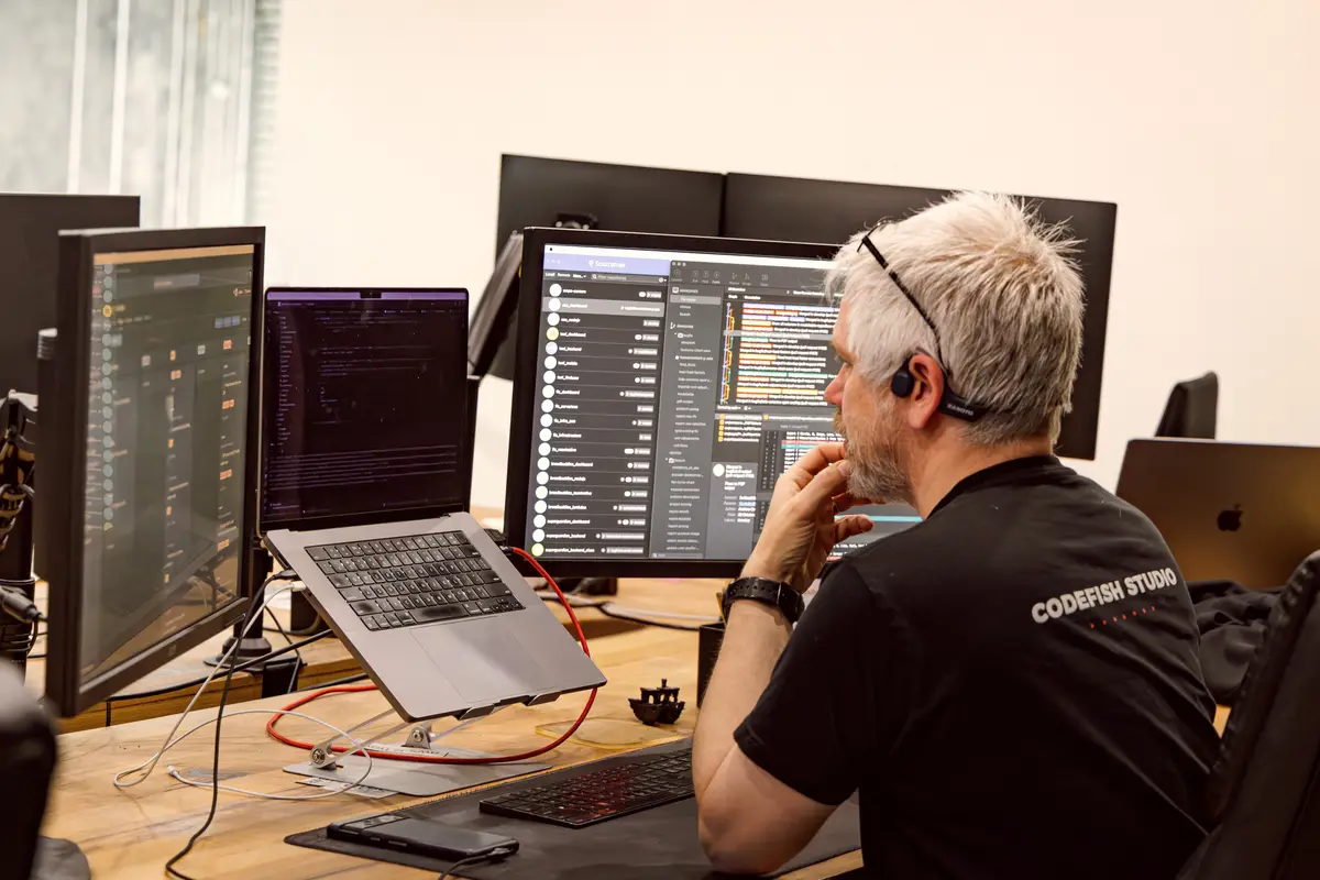 A CodeFish team member reviewing code across several monitors