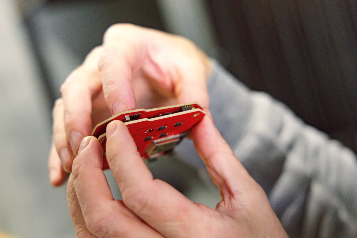 Close-up of hands holding a red printed circuit board