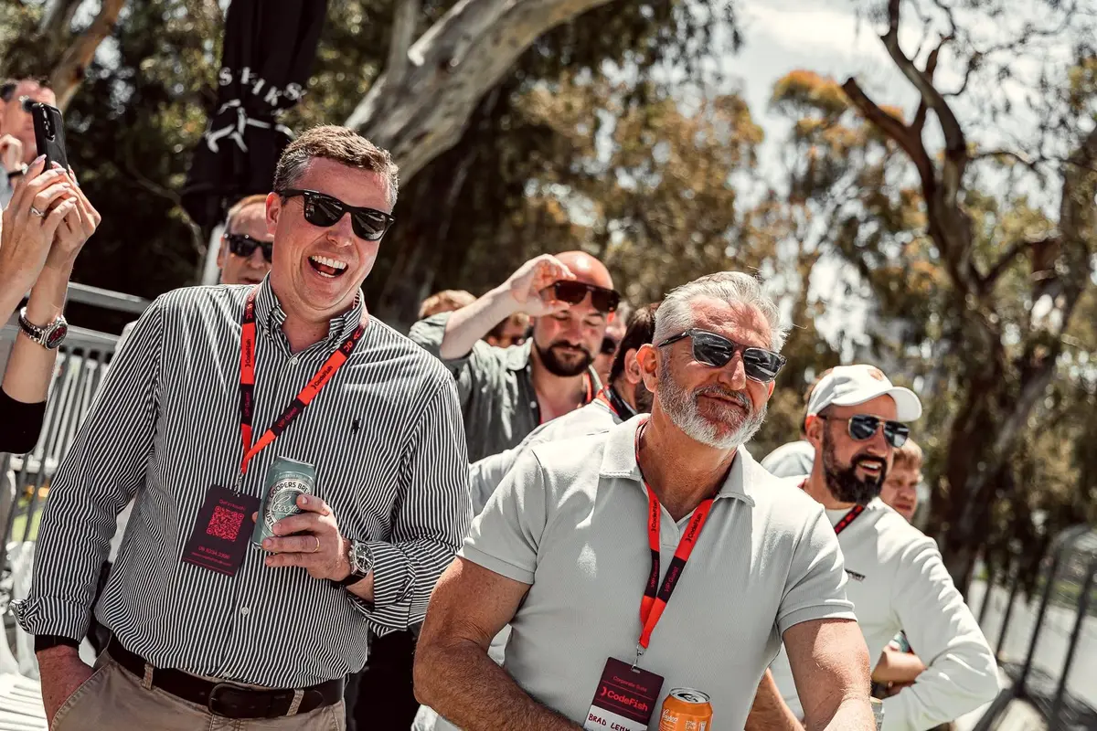 Smiling guests in sunglasses and CodeFish VIP lanyards at an outdoor event