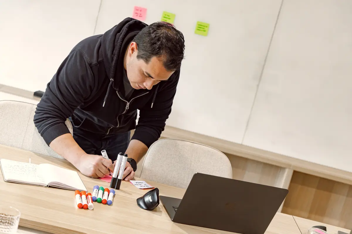 A CodeFish team member writing sticky notes at a workshop table