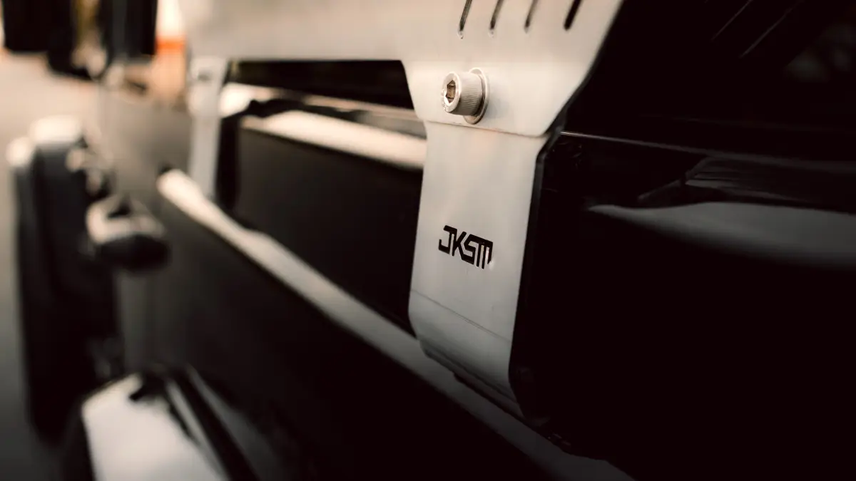 Close-up of a JKSM logo etched into a brushed alloy vehicle mounting bracket