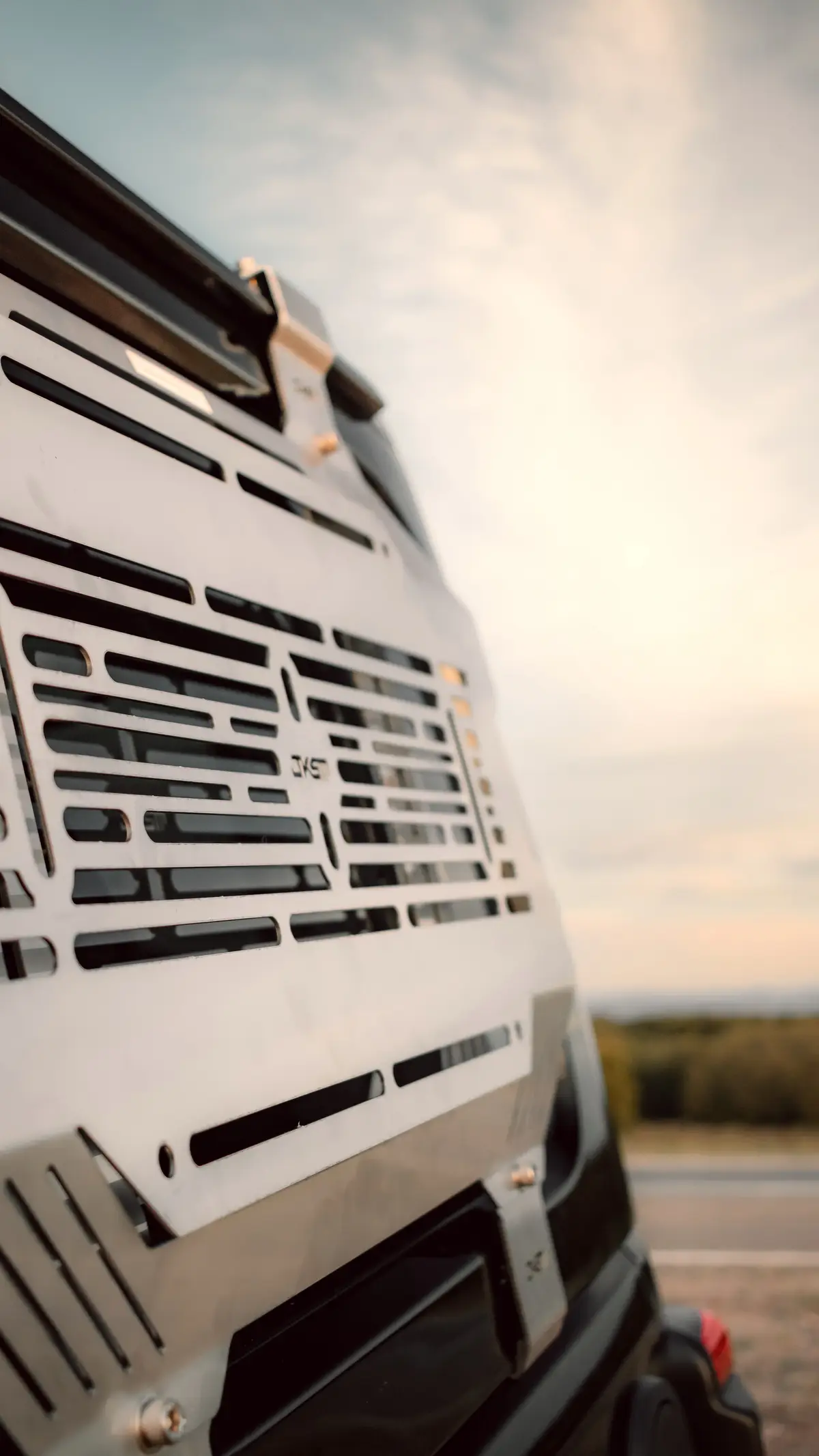 Slotted alloy storage panel on a vehicle window, shot low against an open sky