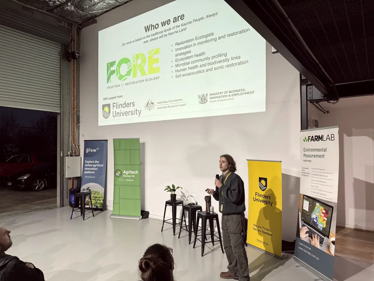 Speaker presenting at an Agritech Meetup SA event with sponsor banners
