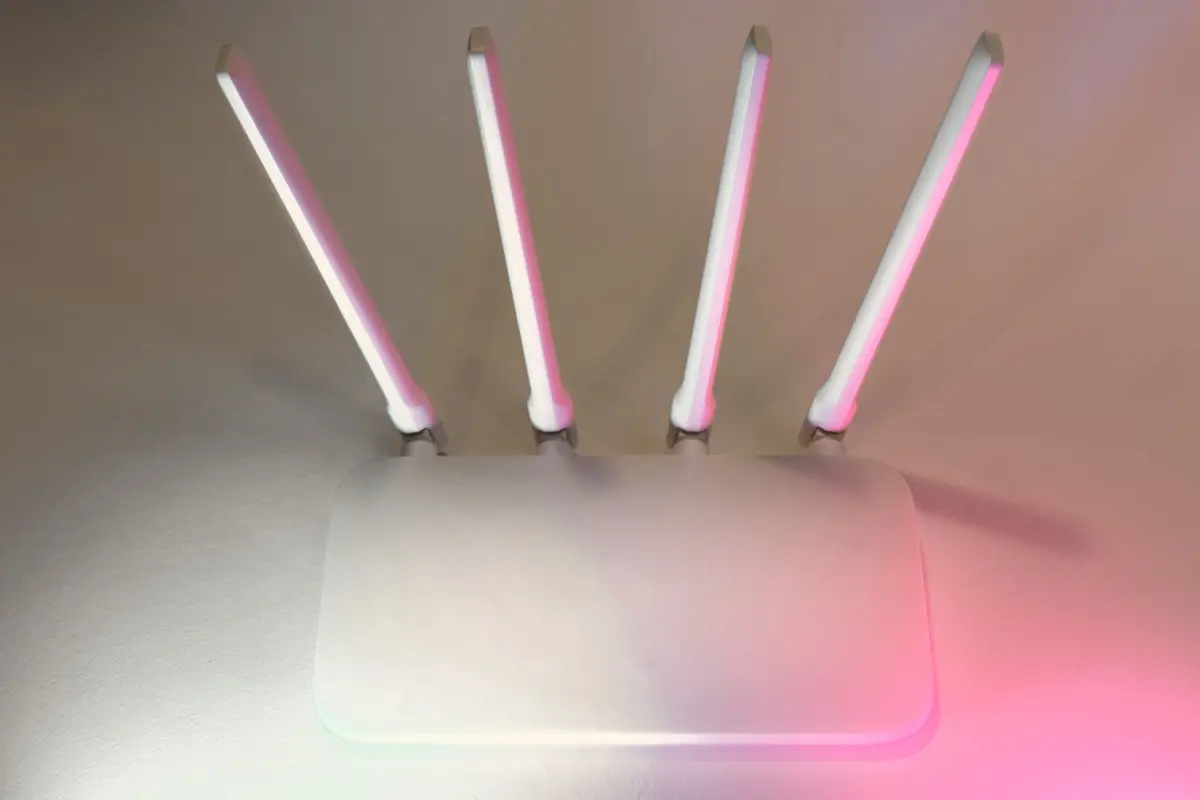 A wireless router with four aerials, lit in pink and cyan light