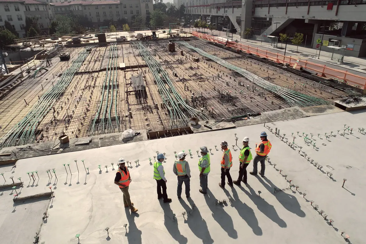 Construction workers in hi-vis vests overlooking a concrete slab site