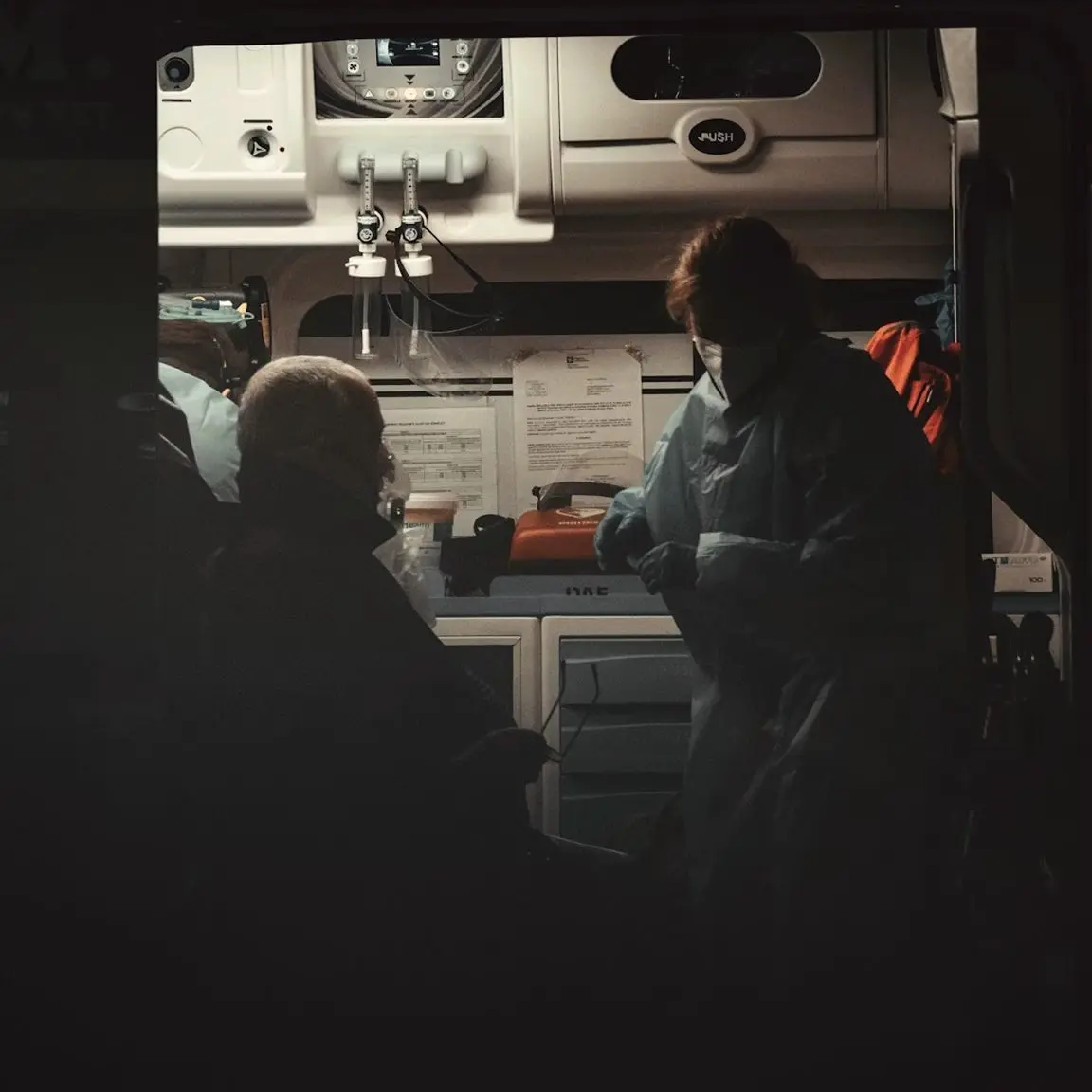Paramedic in protective gear attending a patient inside an ambulance