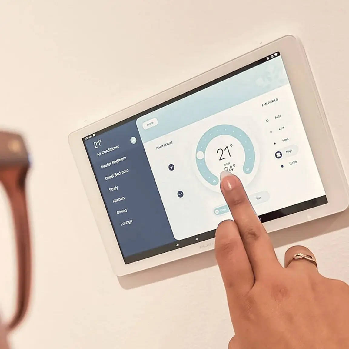 Finger adjusting temperature on a wall-mounted smart home control tablet