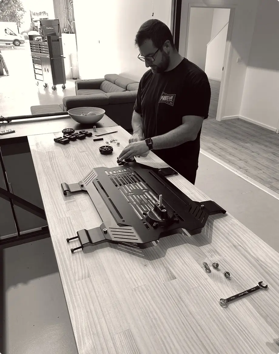 A team member assembling a slotted alloy storage panel on a workbench