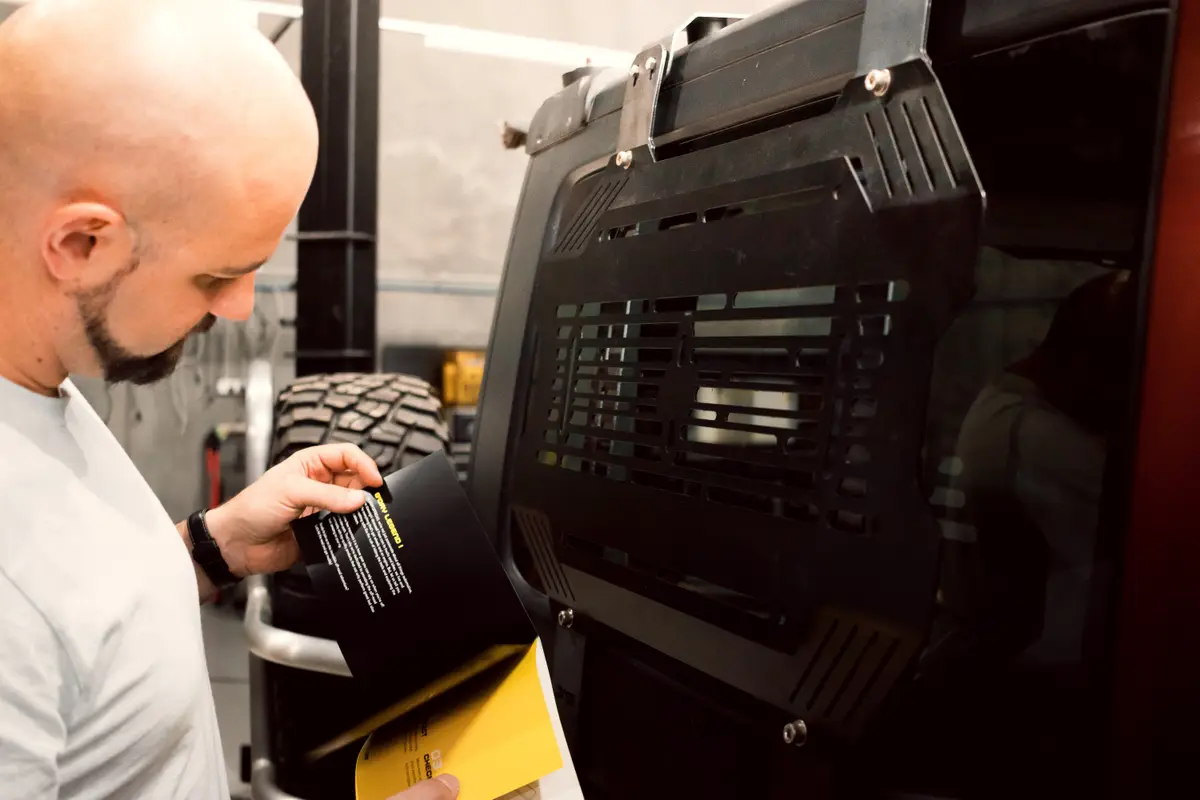 A team member reviewing printed documents beside a black storage panel fitted to a vehicle window