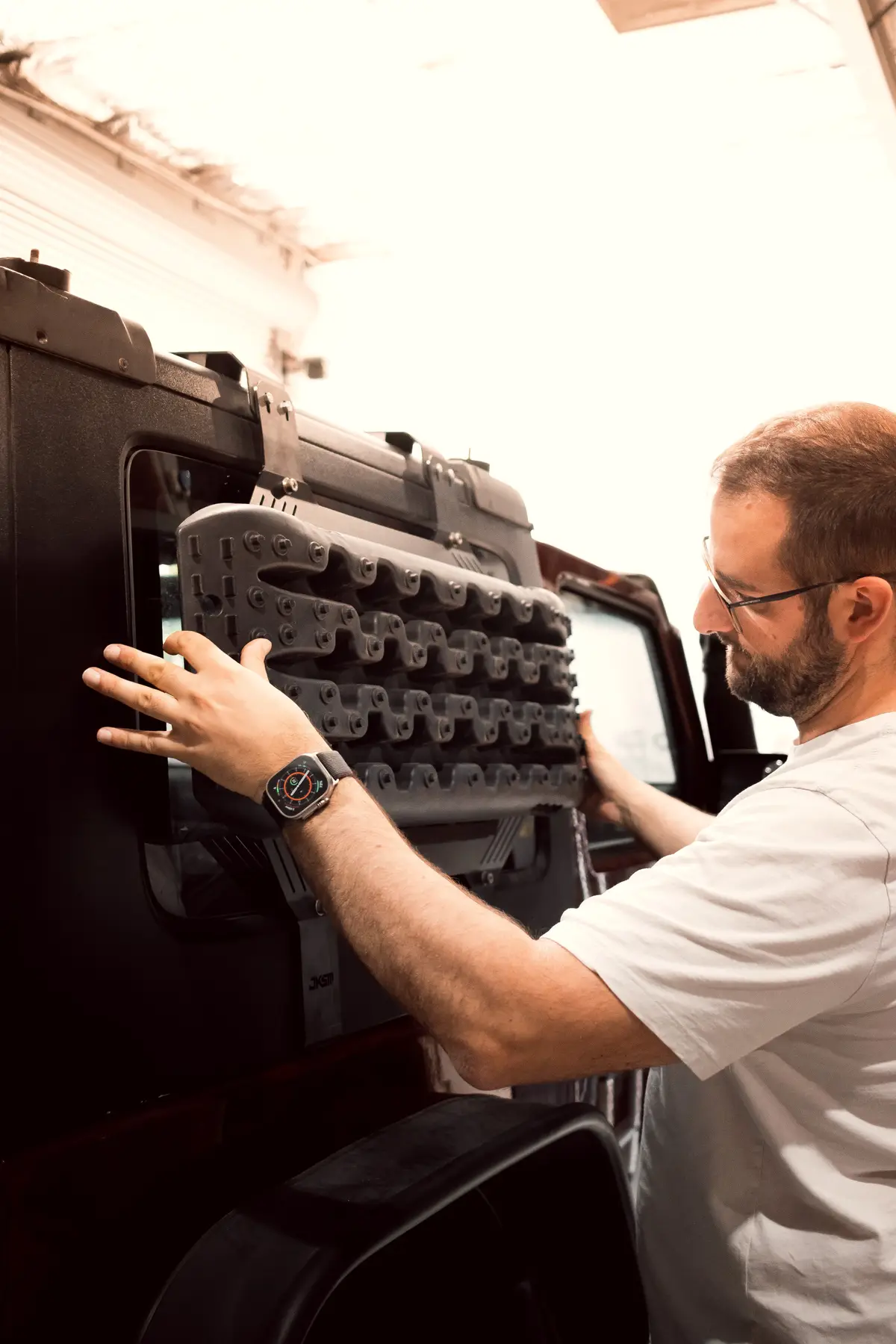 A team member fitting recovery tracks onto a window-mounted storage panel in a workshop