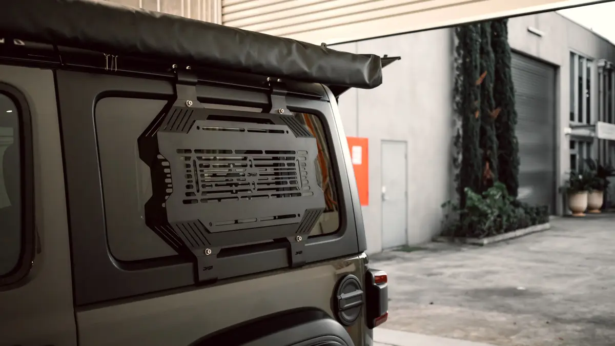 Black JKSM mounting panel fitted over a 4WD rear side window