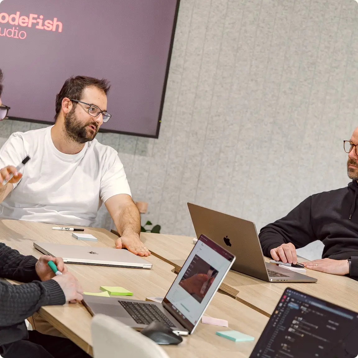 Team discussing ideas around a meeting table with laptops and sticky notes