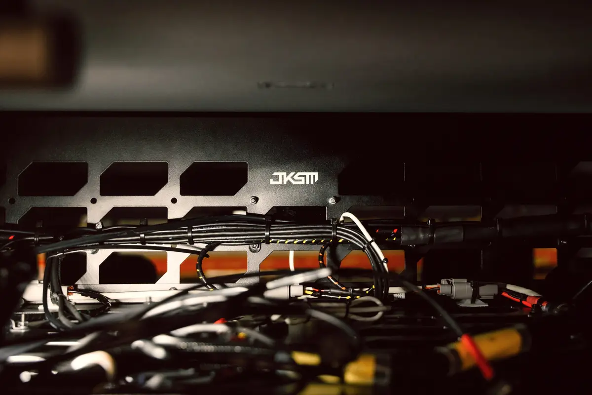 Close-up of wiring harness and cables behind a JKSM metal mounting panel