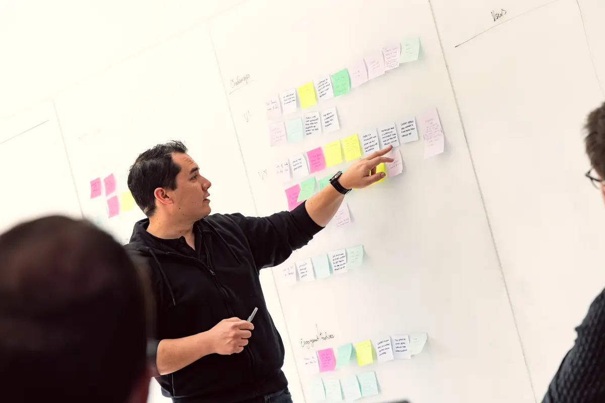 Man pointing at colourful sticky notes on a whiteboard during a workshop