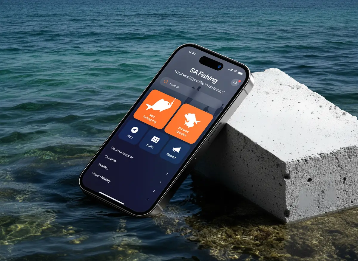 Smartphone showing the SA Fishing app resting on a concrete block by the sea