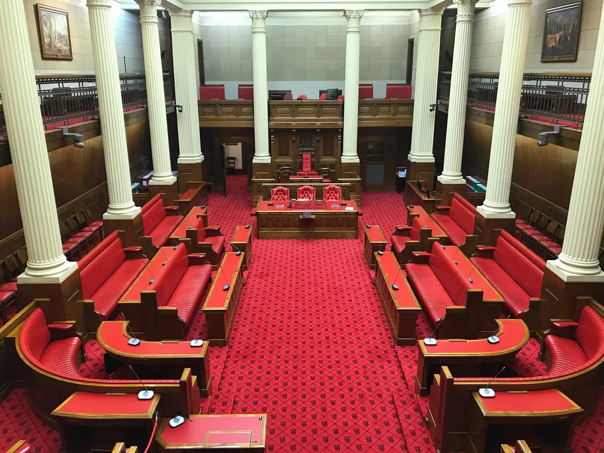 Empty South Australian Legislative Council chamber with red leather benches and white columns