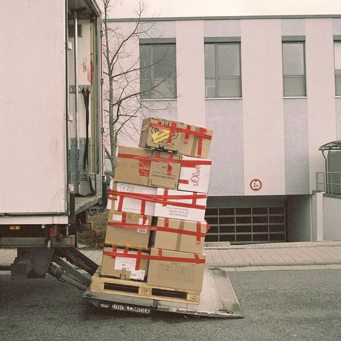 Stack of taped cardboard boxes on a pallet being unloaded from a truck