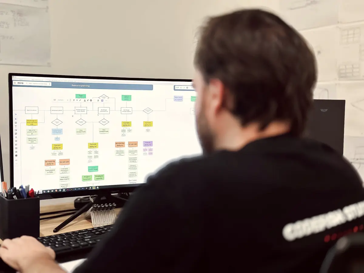 A CodeFish team member reviewing a colourful process flowchart on a monitor